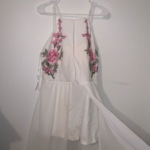 White romper with floral accent embroidery. Lace see through fabric over.